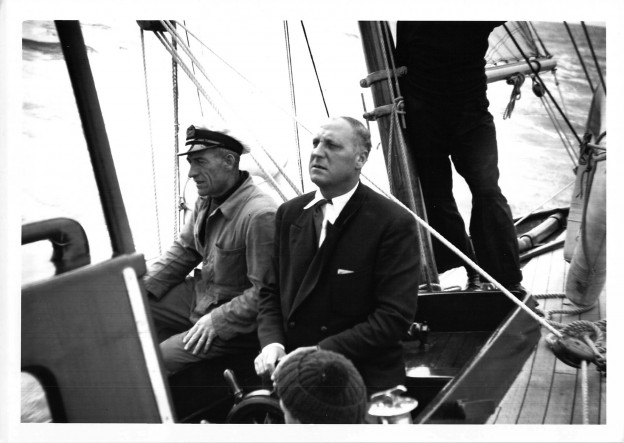 AE Crosby at the wheel of Amokura, with skipper John Roberts